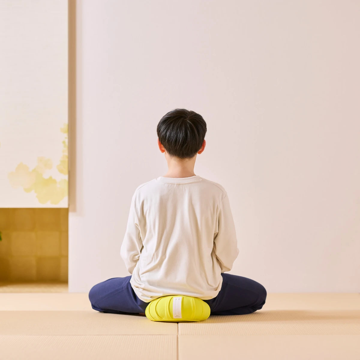 黄色の日本製瞑想クッションに座って瞑想する子供を真うしろから