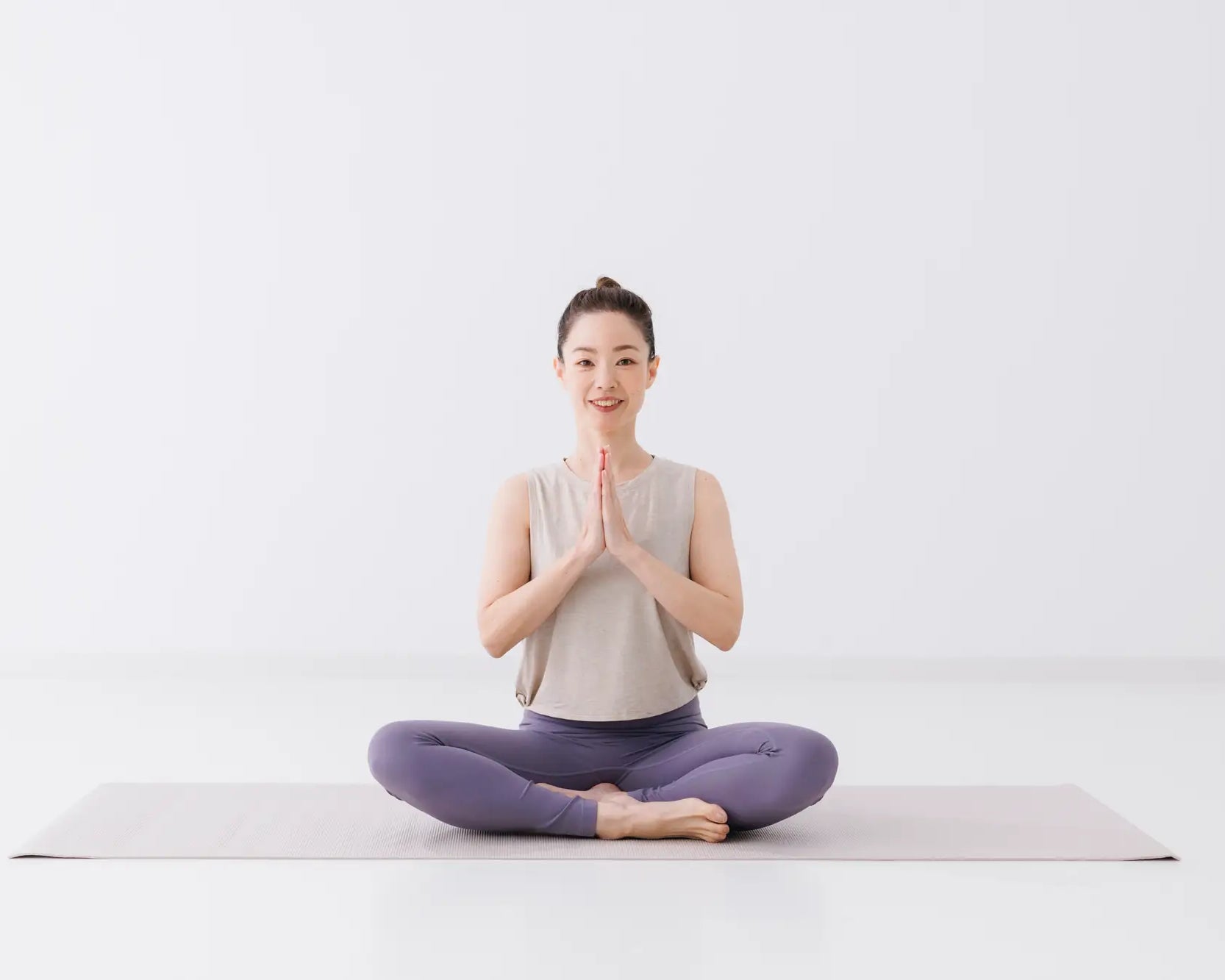 女性のヨガインストラクターが笑顔で合唱している様子