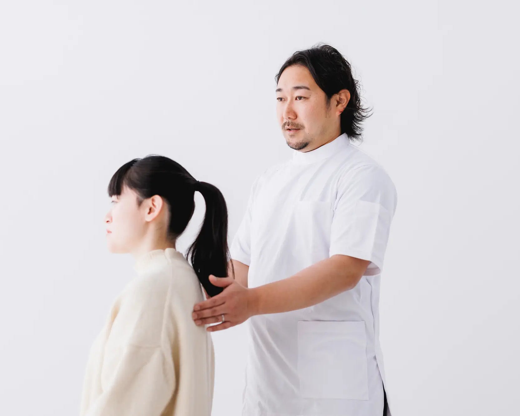 男性の整体師が瞑想クッションに座っている人姿勢をチェックしてコメントしている様子