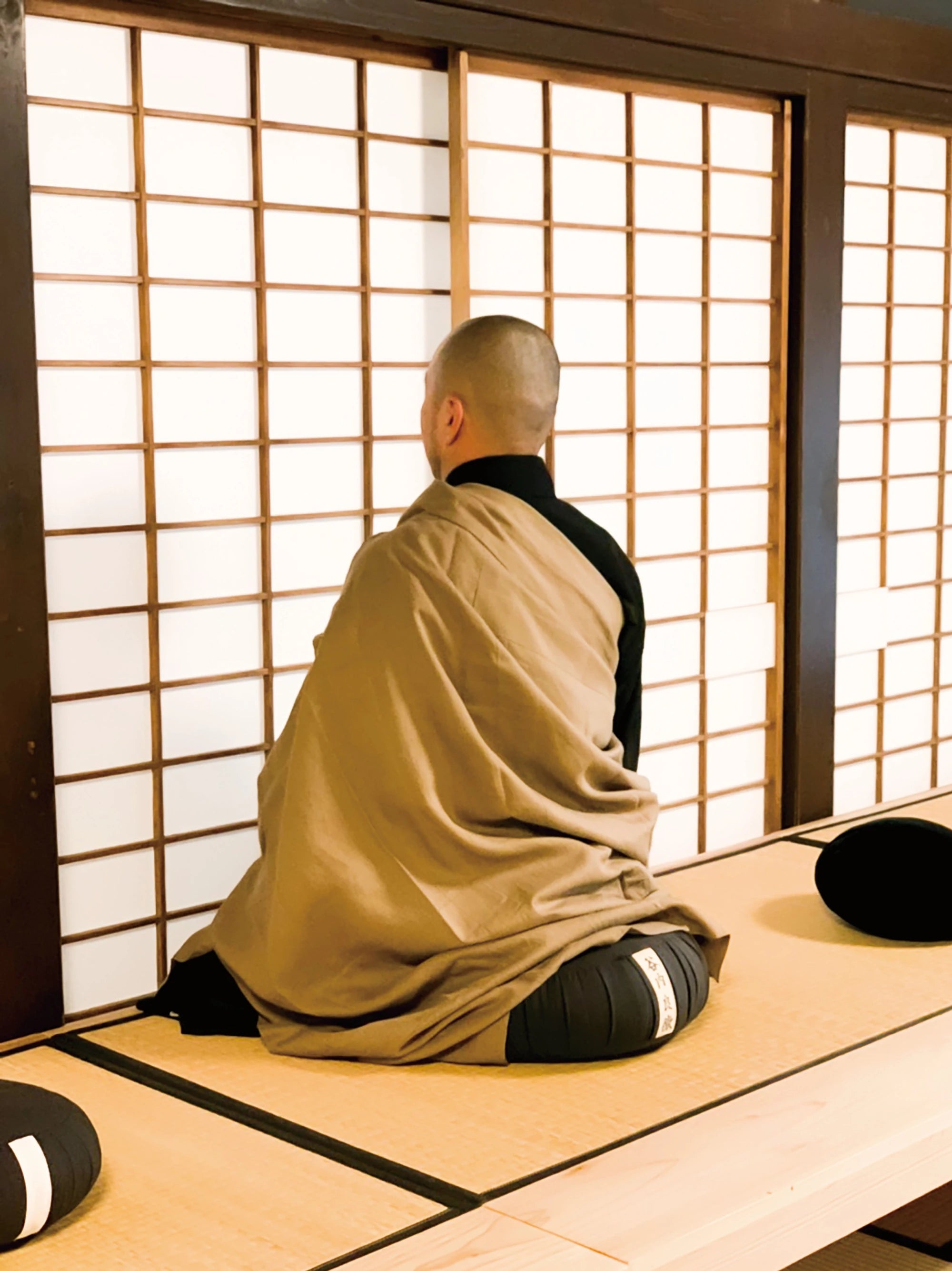 障子に向かって坐禅を組む僧侶