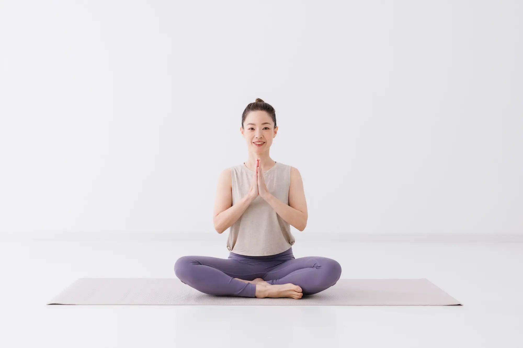 女性のヨガインストラクターが笑顔で合唱している様子
