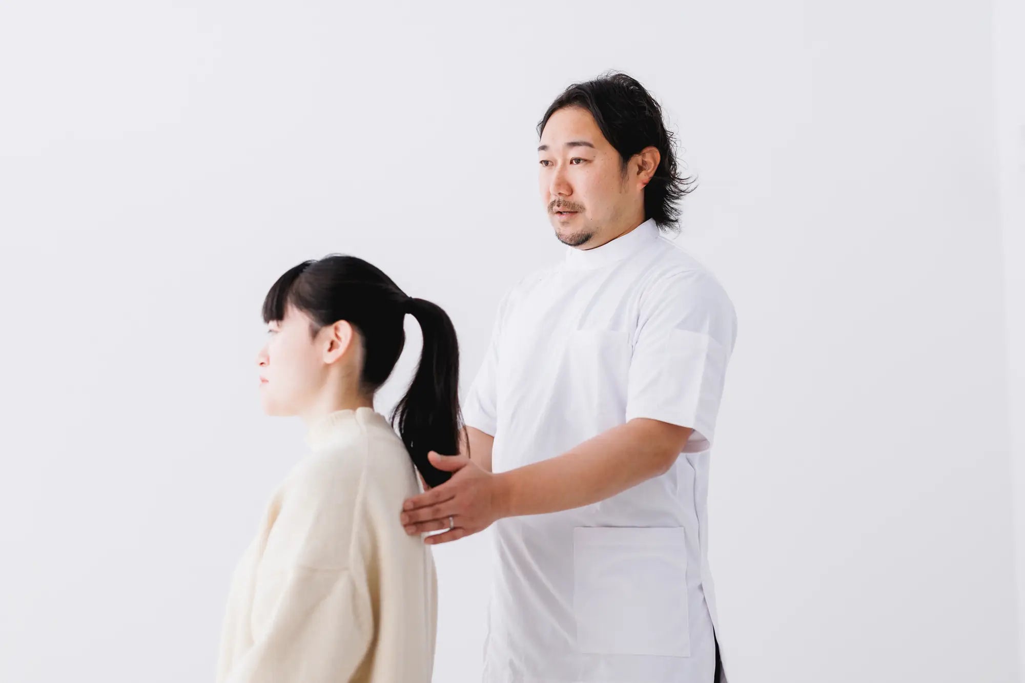 男性の整体師が瞑想クッションに座っている人姿勢をチェックしてコメントしている様子
